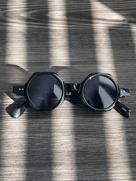 All-black round sunglasses with dark lenses, sleek minimal power shade with edge